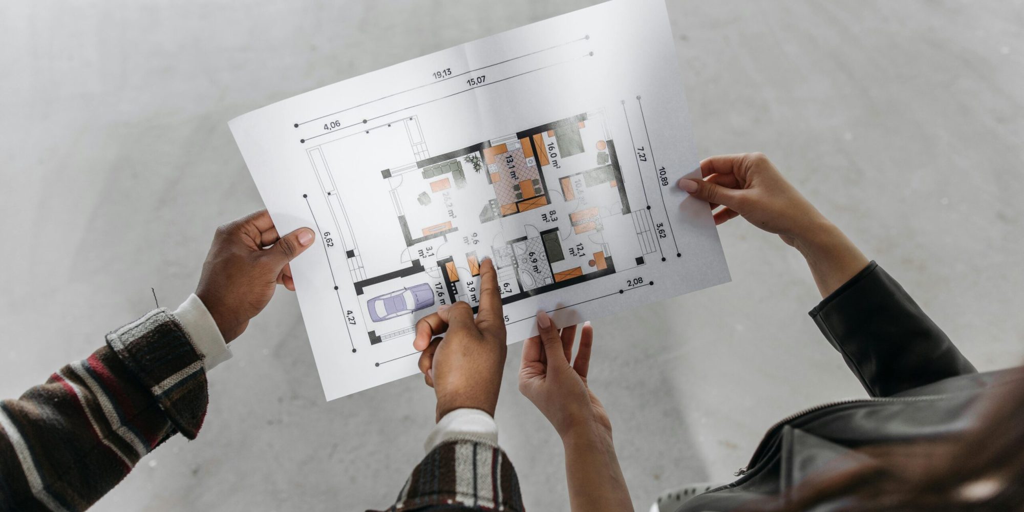 Two people reviewing architectural plans and measuring a new home design.